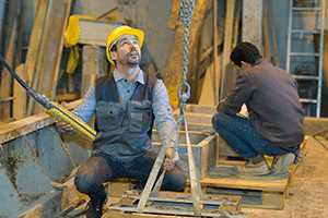 worker with hardhat using a pullet to lift box