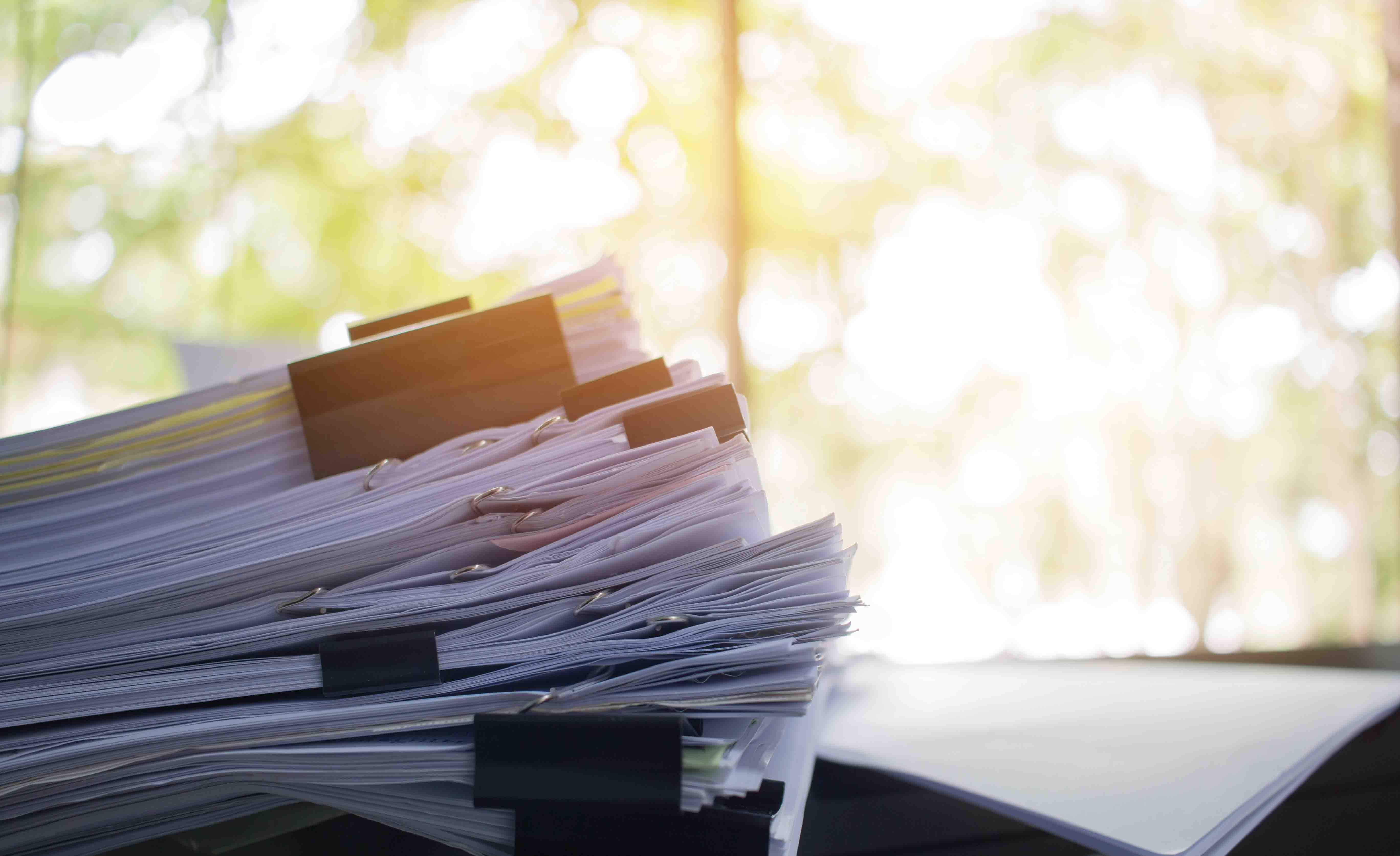 Stack of paper files on work desk in office