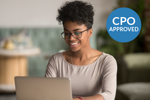 Smiling woman working on a laptop while seated at a desk