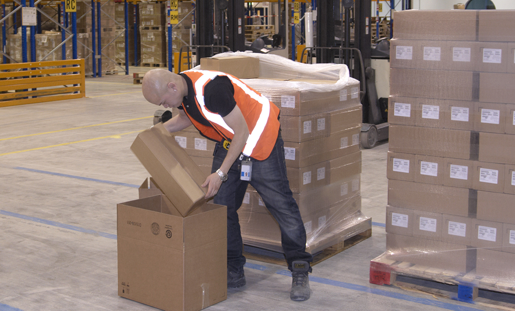 Worker lifting boxes in warehouse