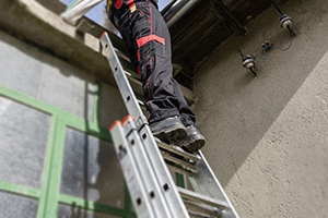Worker on ladder that is leaning against building