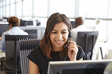 woman sitting at a desk wearing hands free headset while talking to a customer