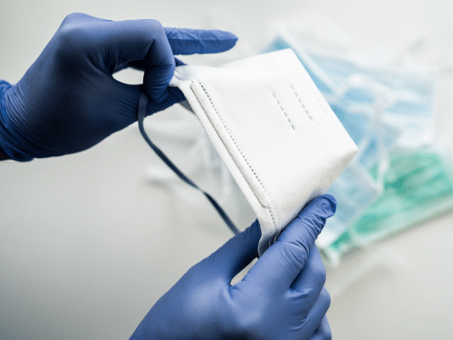Hands wearing nitrile gloves holding a respirator mask