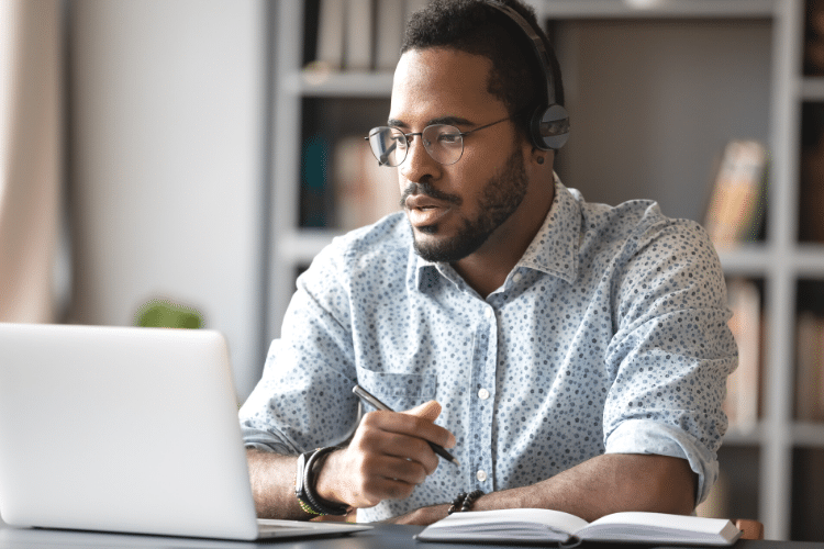 Man wearing headphones while focusing on his laptop while completing a distance learning course