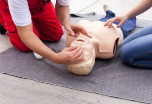 Close up of a pair of hands demonstrating CPR on a first aid mannequin