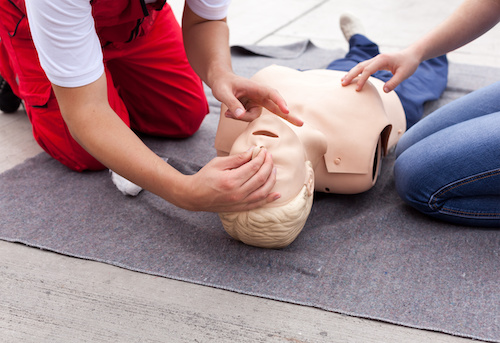 Close up of a pair of hands demonstrating CPR on a first aid mannequin